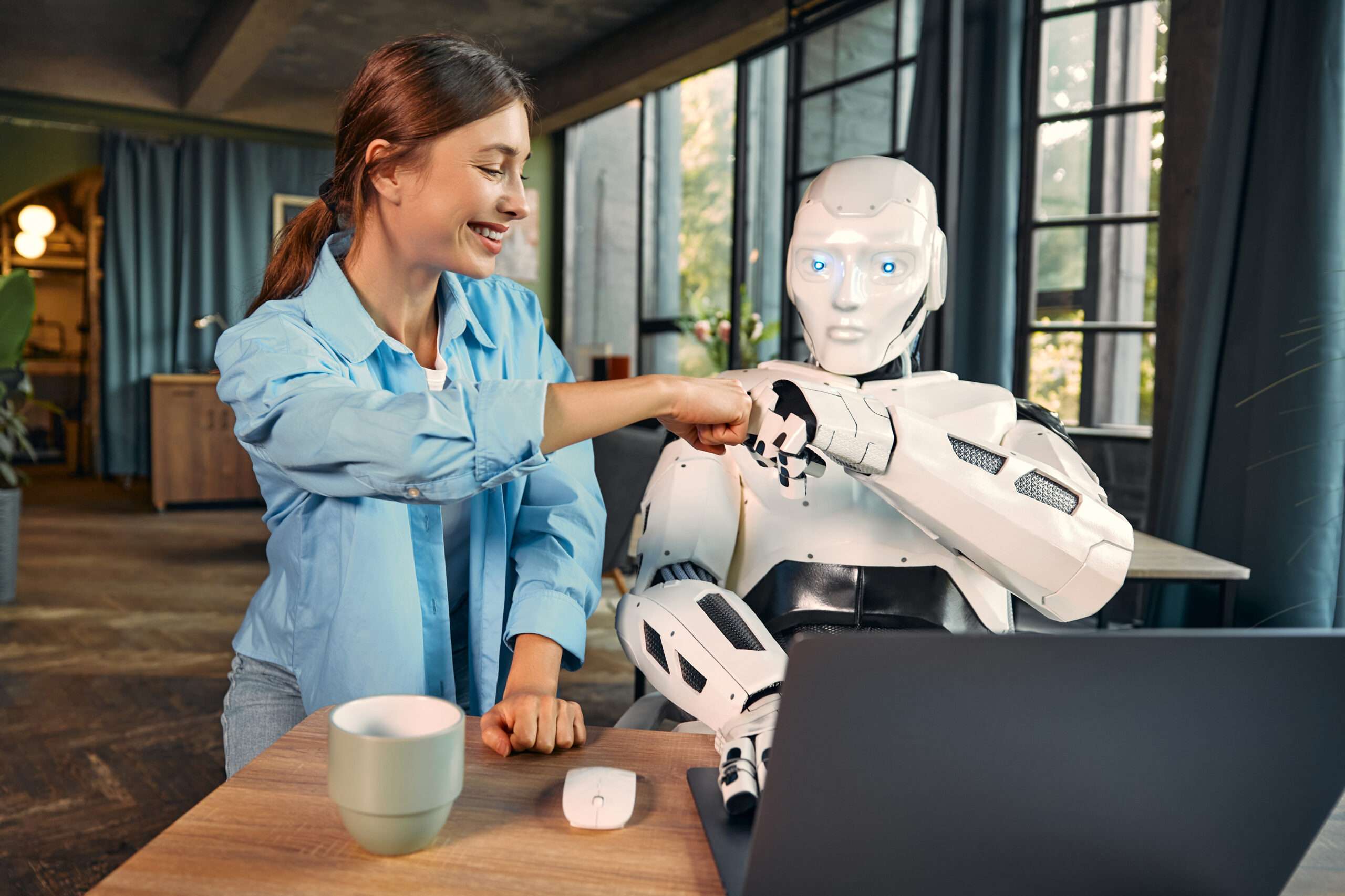 Robot and woman working on laptop in office